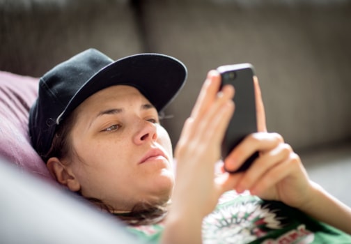 Ung person med caps som ser alvorlig på en mobiltelefon